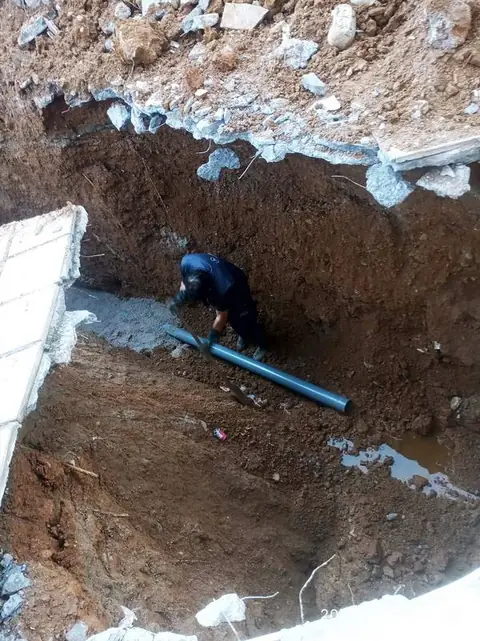 Τεχνικός τοποθετεί αγωγό μέσα σε εκσκαφή